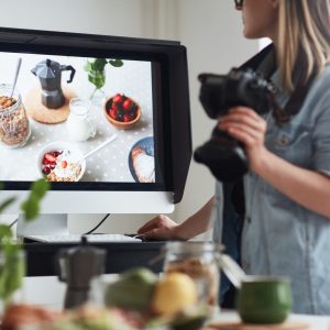 Young food photographer looking at new shot on display of monitor